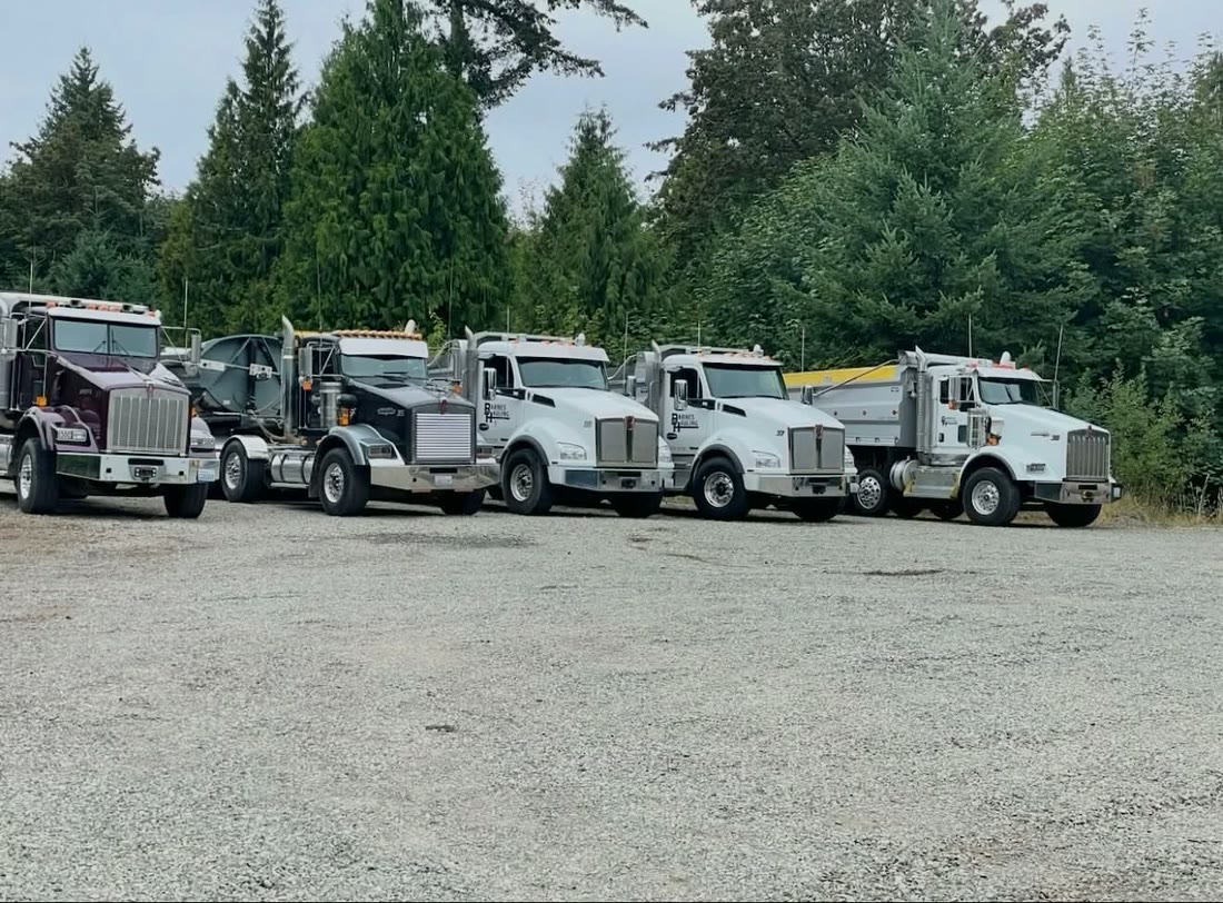Barnes Hauling dump trucks, lined up at the yard and loading on a job site.